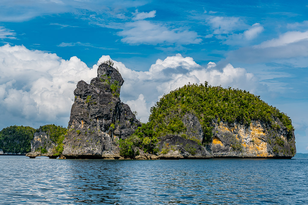Vue plus rapprochée d’une haute aiguille rocheuse et d’un îlot arrondi sur une mer bleue, Waigeo, Raja Ampat, Indonésie
