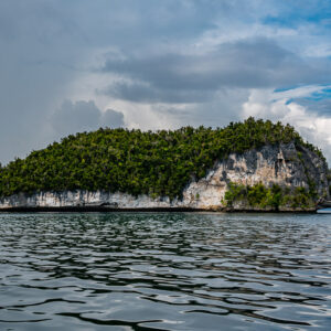 Elongated islet with white undercut cliffs under rain clouds, Waigeo, Raja Ampat, Indonesia