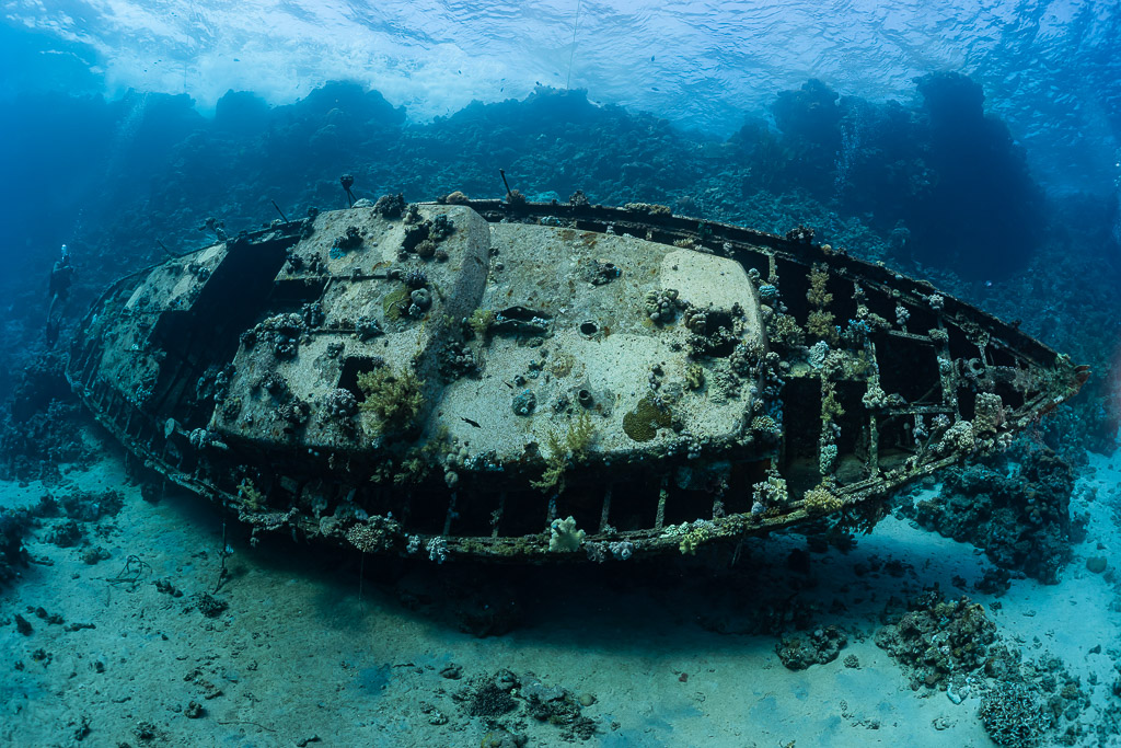 Wreck of a metal sailboat lying on its side on a sandy reef, Red Sea, Egypt