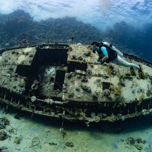Woman diver gliding over the deck of a sunken sailboat wreck, Red Sea, Egypt