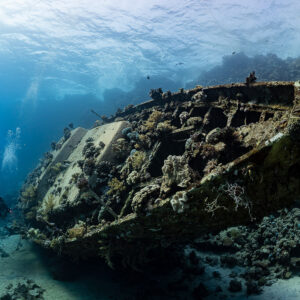 Two divers behind a sunken sailboat wreck, wide-angle view, Red Sea, Egypt
