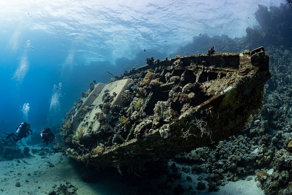 Two divers behind a sunken sailboat wreck, wide-angle view, Red Sea, Egypt