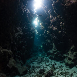 Empty reef cave with light filtering through a vertical crack in the roof, Dangerous Reef South, Red Sea, Egypt