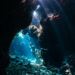Rayons de soleil tombant d’une arche de grotte sur un fond de sable, sans plongeur, grottes de St John's, mer Rouge, Égypte