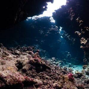 Vue large d’une grotte récifale basse avec ouverture lumineuse et sol rocheux, grottes de St John's, mer Rouge, Égypte