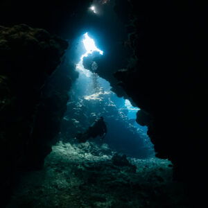 Silhouette de plongeur dans un passage de grotte sombre vers une ouverture lumineuse, Shaab Claudio, mer Rouge, Égypte