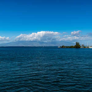 Calm blue sea with a harbour jetty and a distant island on the horizon, Moorea, Society Islands, French Polynesia