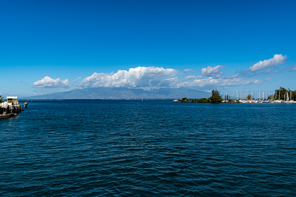 Calm blue sea with a harbour jetty and a distant island on the horizon, Moorea, Society Islands, French Polynesia