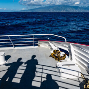 Ferry bow deck with passengers' shadows heading toward a mountainous island, Tahiti, Society Islands, French Polynesia