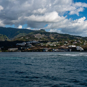 Hillside houses along the coast below cloud-capped mountains, seen from the sea, Tahiti, Society Islands, French Polynesia