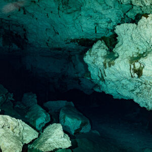 Empty cenote cavern with collapsed limestone blocks under a sculpted ceiling, Quintana Roo, Mexico