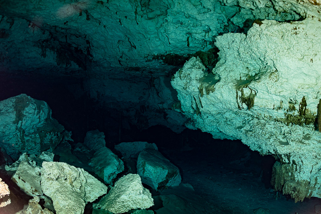 Empty cenote cavern with collapsed limestone blocks under a sculpted ceiling, Quintana Roo, Mexico