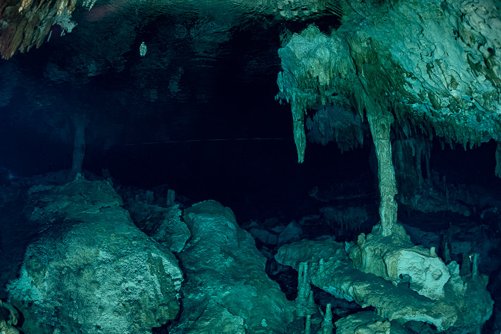 Stalactites and a stalagmite column rising from boulders in a cenote cavern, Quintana Roo, Mexico
