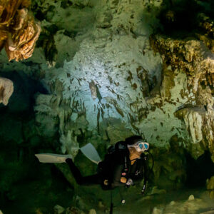 Vue verticale d’une plongeuse avec phare sous des parois richement concrétionnées, Quintana Roo, Mexique