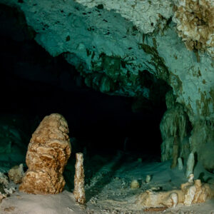 Orange stalagmite and pale speleothems in an empty cenote chamber, Quintana Roo, Mexico