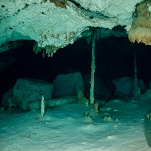 Slender stalactite columns joining floor and ceiling in an empty cenote cave, Quintana Roo, Mexico