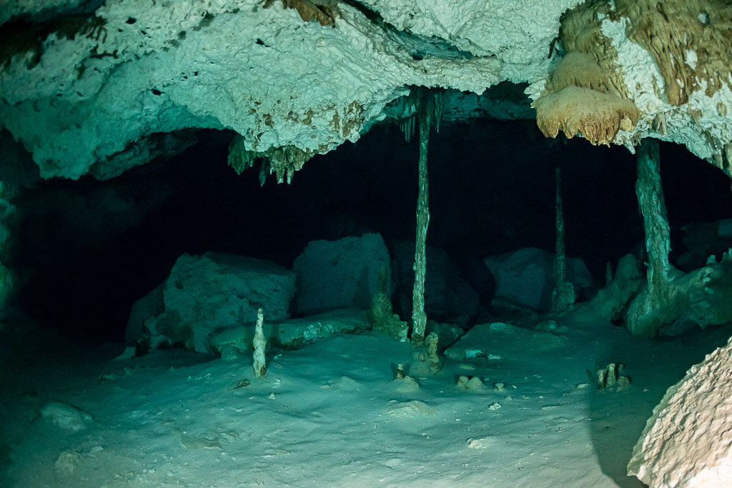 Slender stalactite columns joining floor and ceiling in an empty cenote cave, Quintana Roo, Mexico