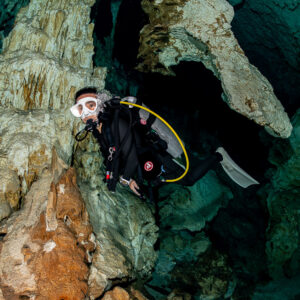 Vue verticale d’une plongeuse se faufilant près d’une coulée calcaire orangée, Quintana Roo, Mexique