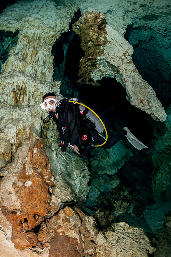 Vue verticale d’une plongeuse se faufilant près d’une coulée calcaire orangée, Quintana Roo, Mexique