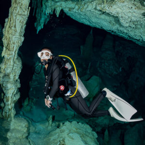 Cavern diver swimming toward the camera between stalagmites and stalactites, Quintana Roo, Mexico