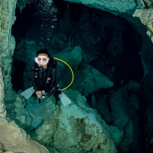 Cavern diver framed by limestone pillars, facing the camera, Quintana Roo, Mexico