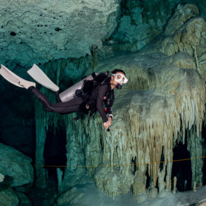 Cavern diver hovering in front of a large flowstone curtain wall, Quintana Roo, Mexico