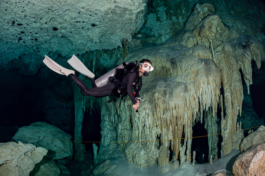 Cavern diver hovering in front of a large flowstone curtain wall, Quintana Roo, Mexico