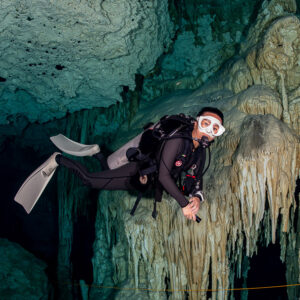Cavern diver close to a flowstone wall, looking at the camera, Quintana Roo, Mexico