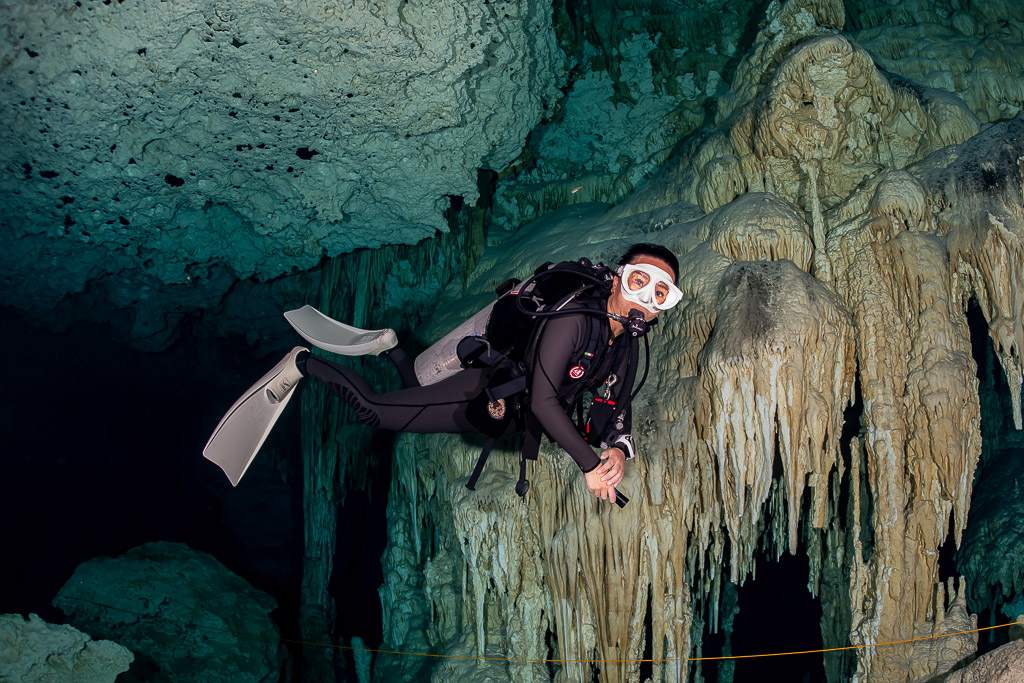Cavern diver close to a flowstone wall, looking at the camera, Quintana Roo, Mexico