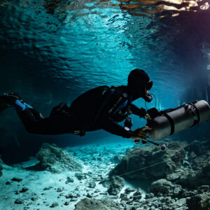 Sidemount diver in silhouette under the mirrored surface of a cenote, Quintana Roo, Mexico