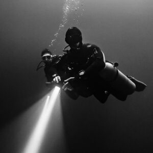 Black and white vertical portrait of a sidemount diver with powerful torch beam, Quintana Roo, Mexico