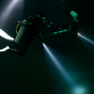Two divers with crossing torch beams in a dark cenote, Quintana Roo, Mexico