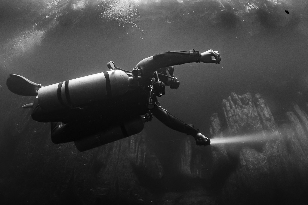 Vue rapprochée en noir et blanc d’un plongeur sidemount tendant son phare, Quintana Roo, Mexique