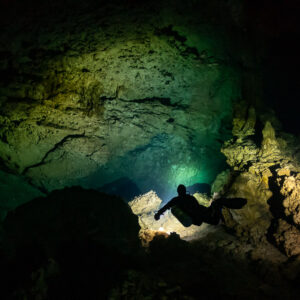 Small diver silhouette dwarfed by a large rocky cavern, Quintana Roo, Mexico