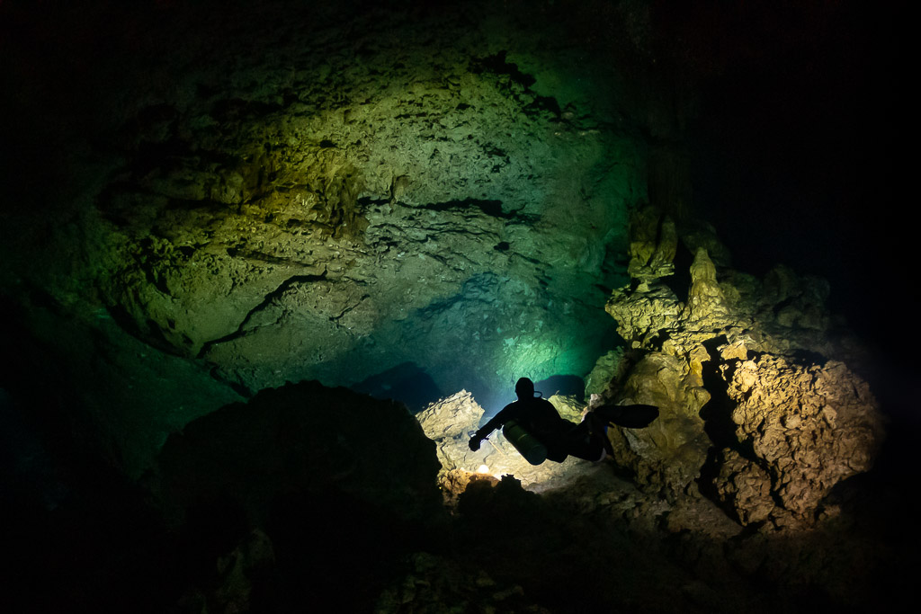 Small diver silhouette dwarfed by a large rocky cavern, Quintana Roo, Mexico