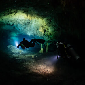 Two divers with torches in a dark decorated cave, wide view, Quintana Roo, Mexico