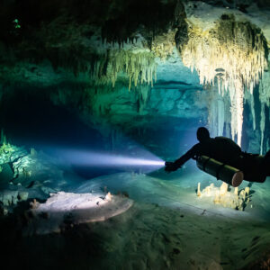 Sidemount diver beaming a torch across a white silt mound in a cave, Quintana Roo, Mexico