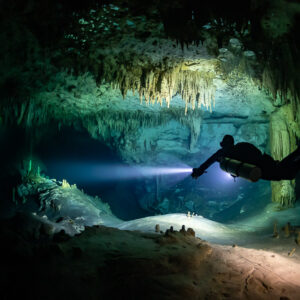 Sidemount diver lighting a cave room with stalactites and white floor, Quintana Roo, Mexico