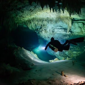Sidemount diver gliding past a pale silt dune and the guideline, Quintana Roo, Mexico