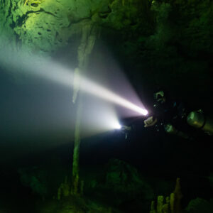 Sidemount diver with two powerful torch beams in a dark cave, Quintana Roo, Mexico