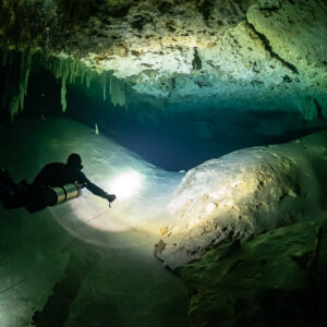Sidemount diver lighting a smooth white rock dome in a cave, Quintana Roo, Mexico