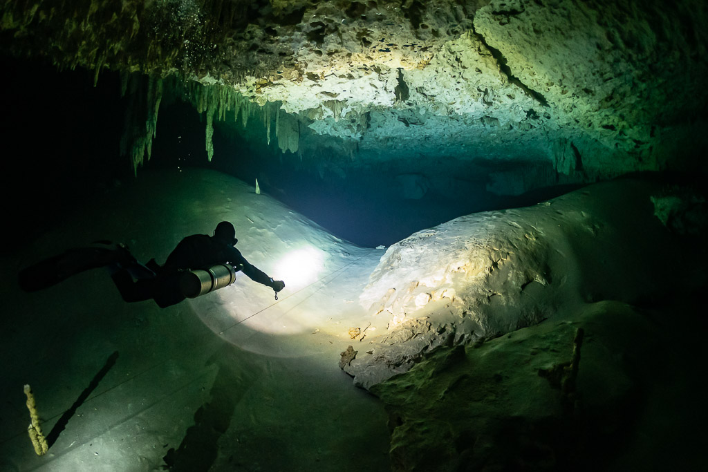 Sidemount diver lighting a smooth white rock dome in a cave, Quintana Roo, Mexico