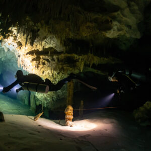 Two divers lighting stalagmites and a decorated chamber, Quintana Roo, Mexico