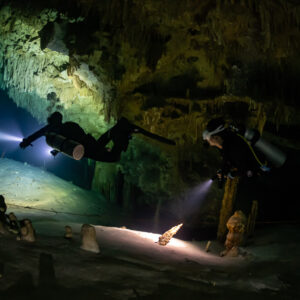 Two divers with torches among small stalagmites on a sandy floor, Quintana Roo, Mexico