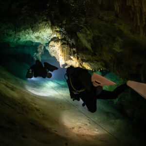 Two divers on a slope in a cave, white fins in the foreground, Quintana Roo, Mexico