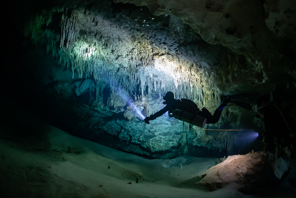 Sidemount diver lighting curtains of stalactites along the guideline, Quintana Roo, Mexico