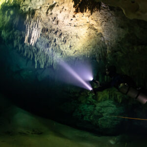 Two divers with torches under a low stalactite ceiling, Quintana Roo, Mexico
