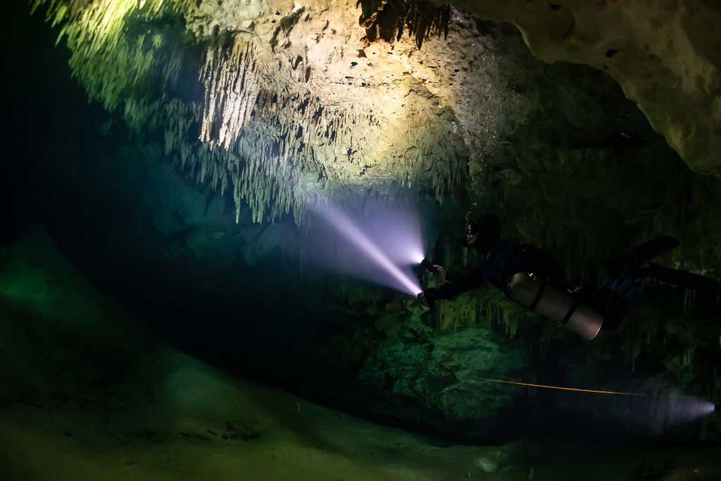 Two divers with torches under a low stalactite ceiling, Quintana Roo, Mexico
