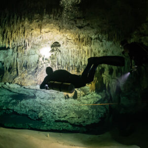 Two divers in silhouette crossing a cave room with bubbles, Quintana Roo, Mexico