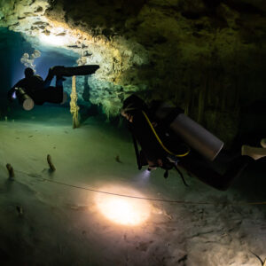 Two divers along the guideline, backmount diver lighting the sand, Quintana Roo, Mexico